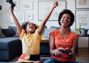 A mom and daughter play video games together at home